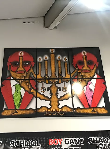 the artists are pictured in a bright red style with a menorah right across the image in gold that is shaped at the edges to give them a beard, and at the bottom of the image it says beardlight