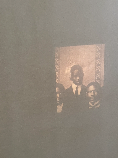 a projection directly onto the wall shows a faint photograph of three black people taking a portrait