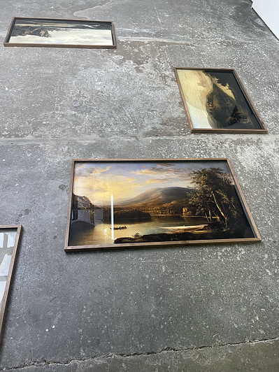 on the floor, there are various framed prints of landscape paintings