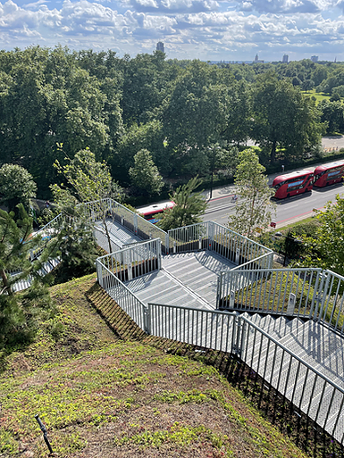 green park is visible, two red buses, and a zig zag of white metal steps between the built mound