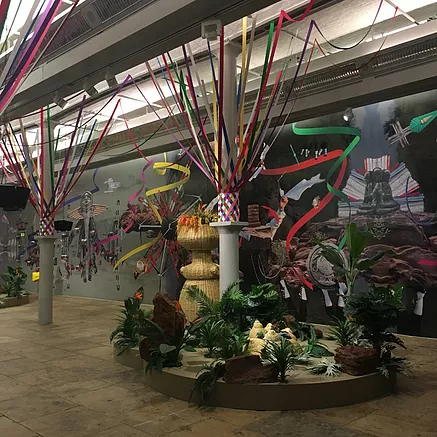 the lower gallery space in tate liverpool is full of plants around the columns, which are wrapped with ribbons going right up to the ceiling