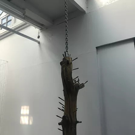 a log hangs down from a chain on the ceiling, and it looks like it has spliffs poking out of it in many places like tiny branches