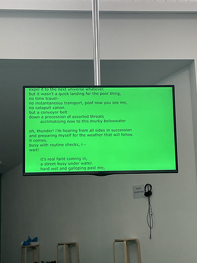 a flat screen shows a green neon with a poem on it