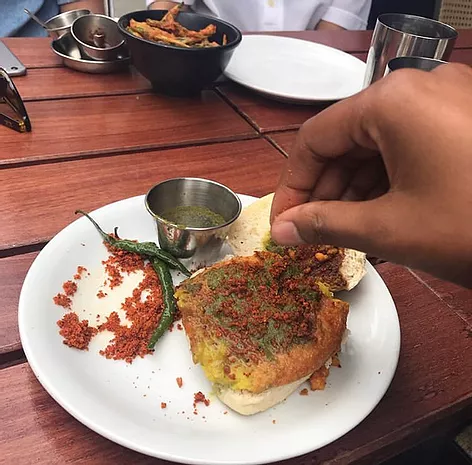 Zarina has a hand in front of her taking some food from a plate