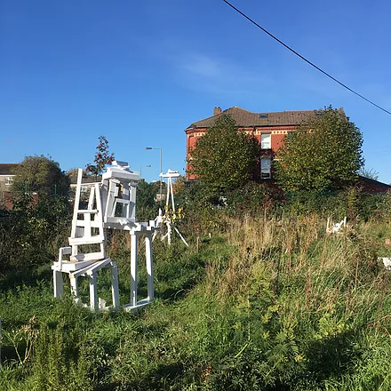 some hodgepodge white wooden sculptures in an overgrown field in toxteth