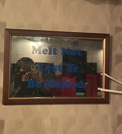 a mirror has a decal over it that says melt not lest ye be melted and zarina is taking a picture in it