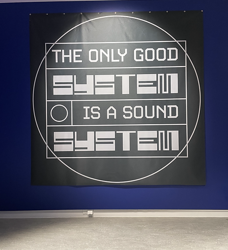 a big black flag on the wall with white text says the only good system is a sound system