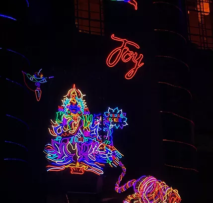 a neon of a hindu god full of twiddly colours all smushed together below a red word that just says Joy