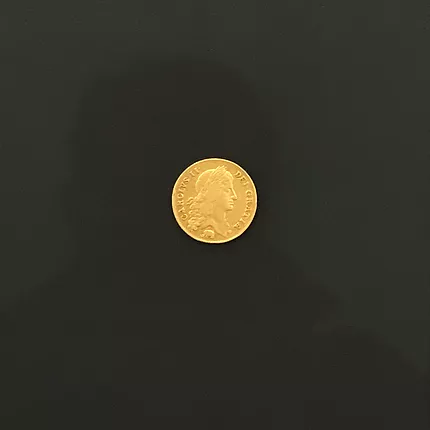 a coin, a two guinea piece against a black background