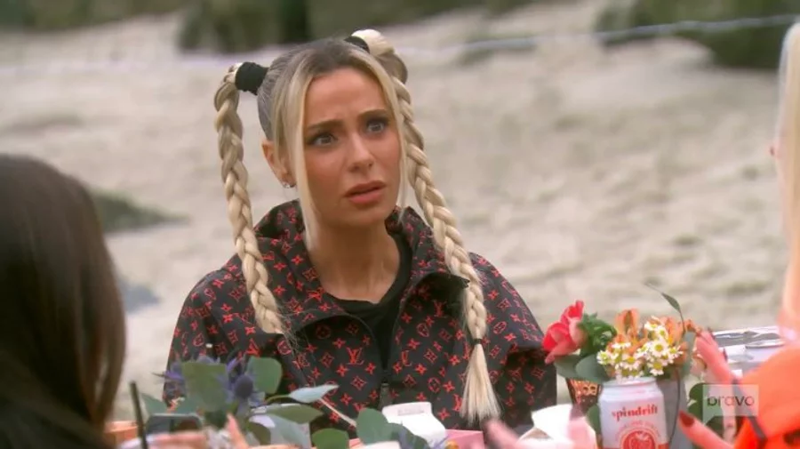 Dorit looks confused at someone off camera but more importantly she has her hair in two high pigtail plaits
