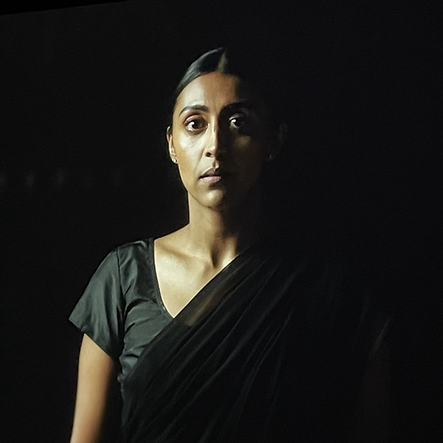 a photograph of a real life brown woman wearing black fabric over her body against black space