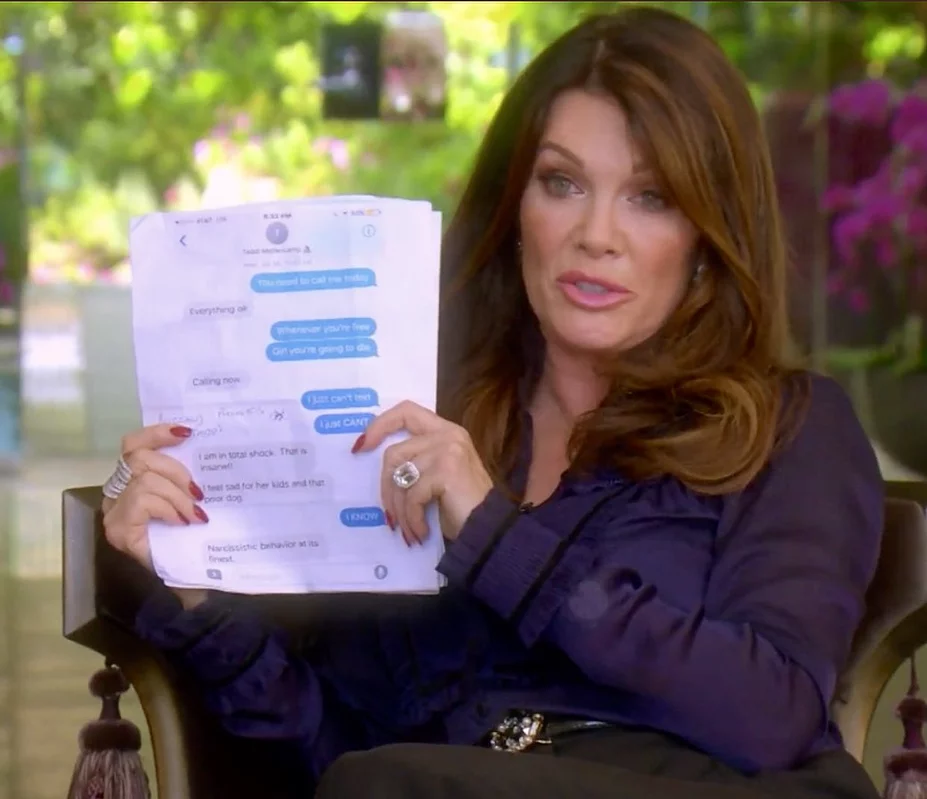 Lisa Vanderpump holds up printed off screenshots of texts at the camera