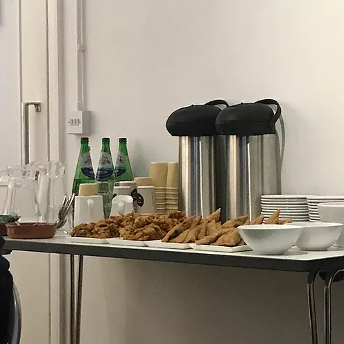 a table at an event with refreshments - I can see samosas and sparkling water