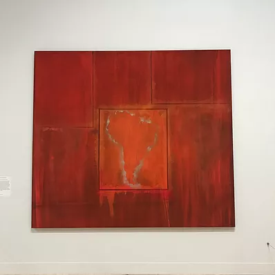 an abstract painting in burnt orange with streaks, and at the centre in a rectangle is the vague outline of South America
