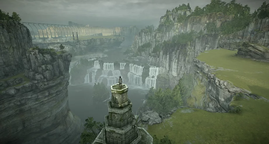Wander is stood at the top of a pyramidal stack of columns that get smaller and smaller, looking forward down onto waterfalls a mile away, and the bridge from the beginning of the game is visible even further away, between more cliffs and fields