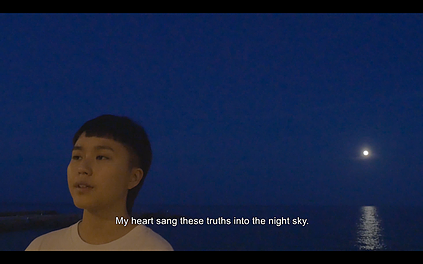 someone stands just about lit in front of a nighttime sky with the moon reflecting onto the sea, and the caption says my heart sang these truths into the night sky