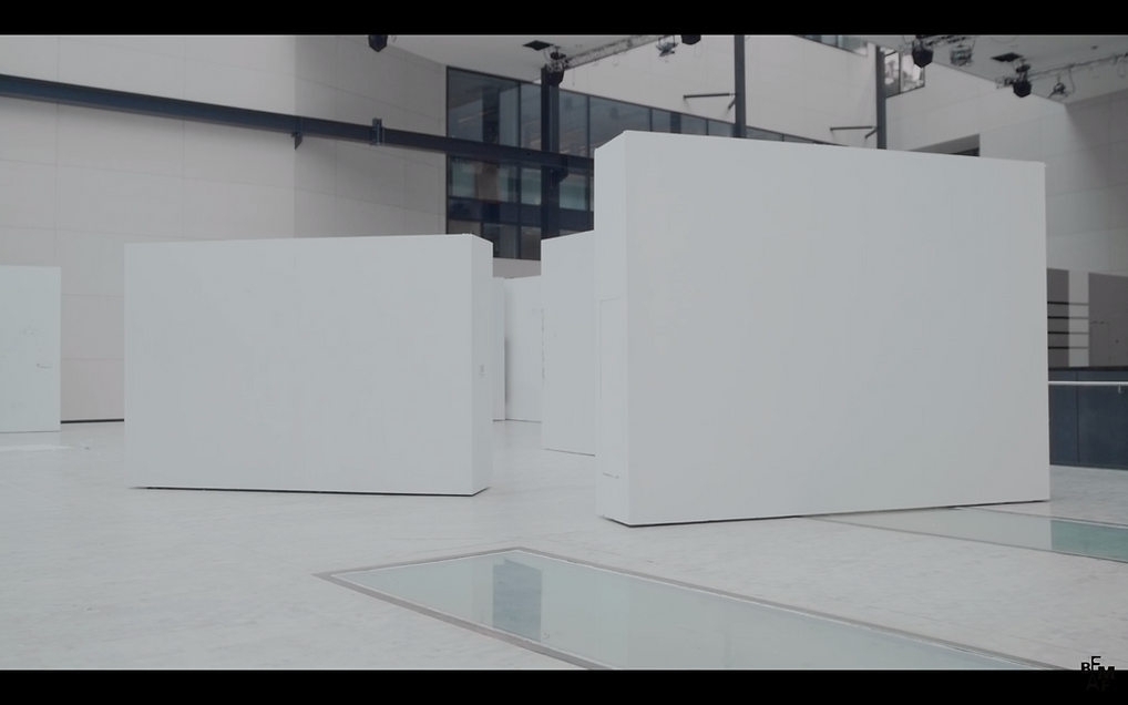 a white exhibition space shows a bunch of standalone white walls in diagonals across the space