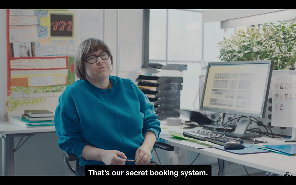 a white woman in an office space says thats our secret booking system
