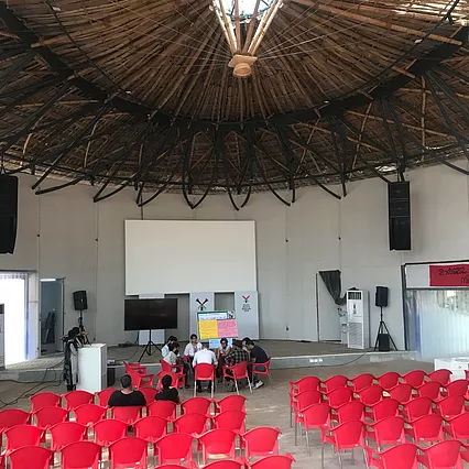 the workshop is taking place in the centre of a huge circular room with a wooden ceiling, and there&rsquo;s a group visible in the centre of the room on red chairs huddled together