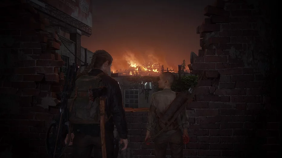 Abby and Lev stand next to a broken wall looking over a village on fire at night