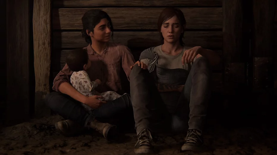 Dina and Ellie sit next to each other on the floor while breathes deeply after a panic attack, and Dina holds the baby in one arm while she attends to both