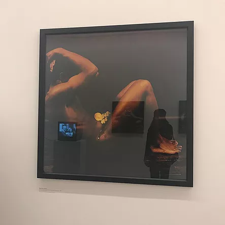 a framed photograph of a Black body with arms up over the head hiding the face and barely lit so that just the arms and the legs and the tops of the feet are visible against no light