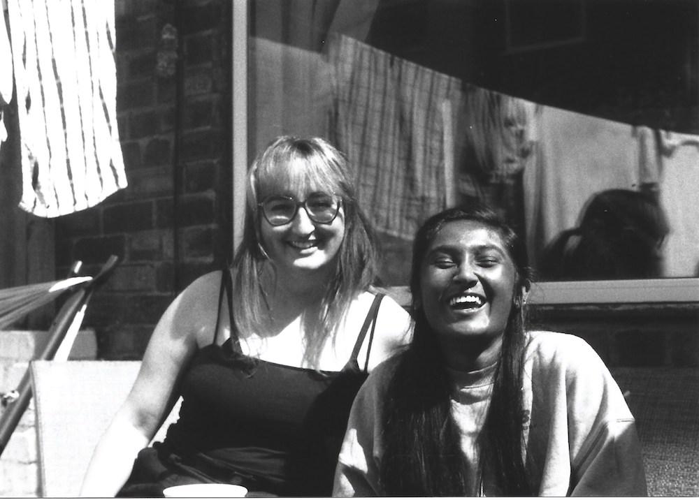 black and white film photo of gab and zarina mid laugh on a sunny day