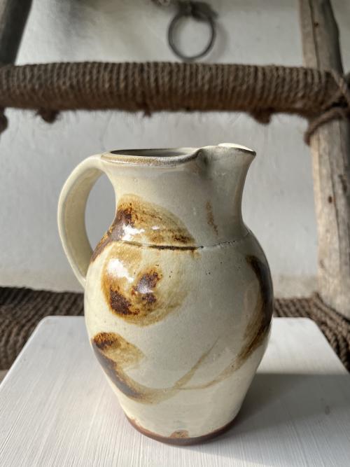 a jug in a rustic beige colour with a brown swipes around the body