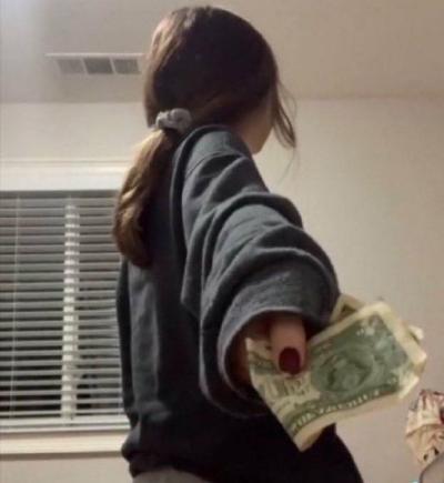 a girl with her hand behind her back giving the person behind her some money