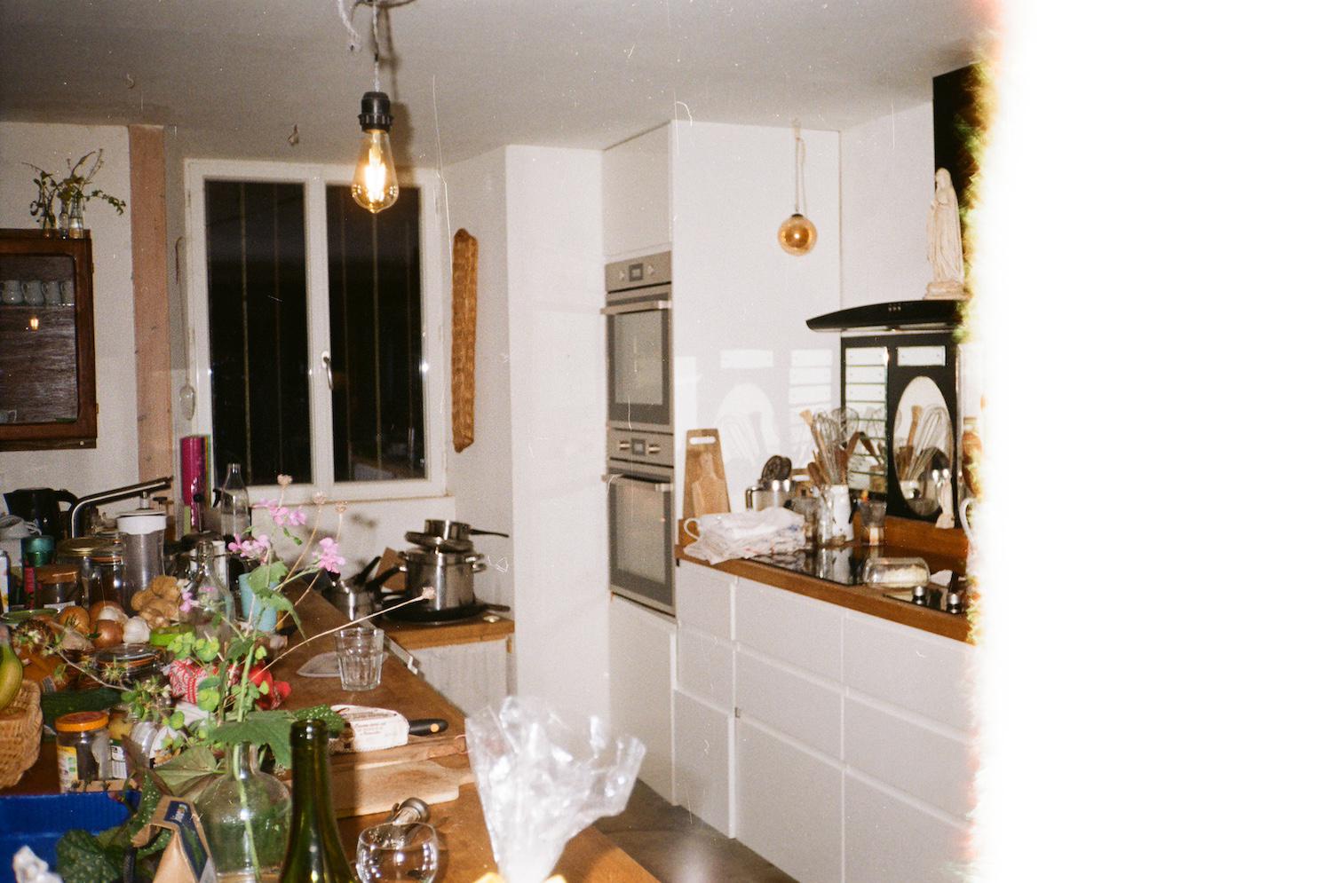 the film roll starts at one end so some of the image of a kitchen is cut off, but you can see white cabinetry and a double oven, an exposed lightbulb, and flowers on the counters