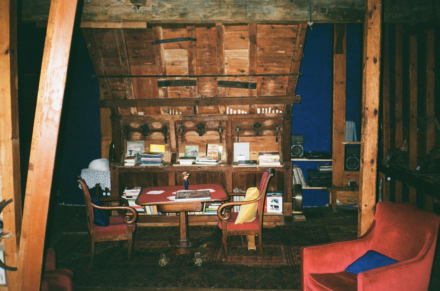 a wooden chute in a room with blue walls, with books and vinyls on shelves in front and to the side of the chute feature which originates from the building being an old mill