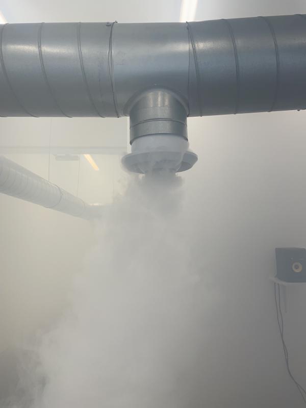 closeup of a nozzle on a silver pipee, ejecting a thick cloud of mist